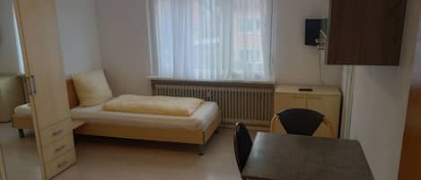 Una habitación pequeña con cama, escritorio y silla.