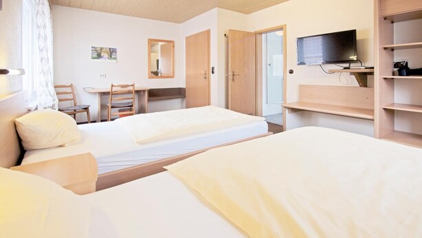 A hotel room with two beds, a desk, a chair, a TV, and a wardrobe. - Hotel Victoria (Weil am Rhein)