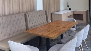 A modern dining area with a wooden table, grey upholstered chairs, and a tufted sofa. - Baypark Inn (Calbayog)