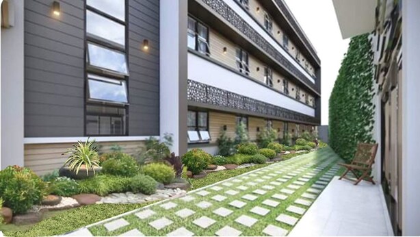 A modern building with a covered walkway, potted plants, and a neatly arranged garden. - Baypark Inn (Calbayog)
