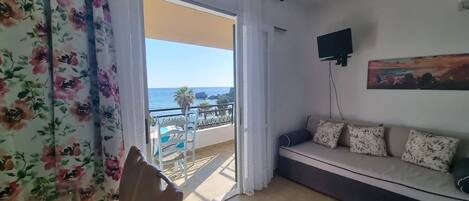 A room with a balcony, a sofa, and a painting on the wall.