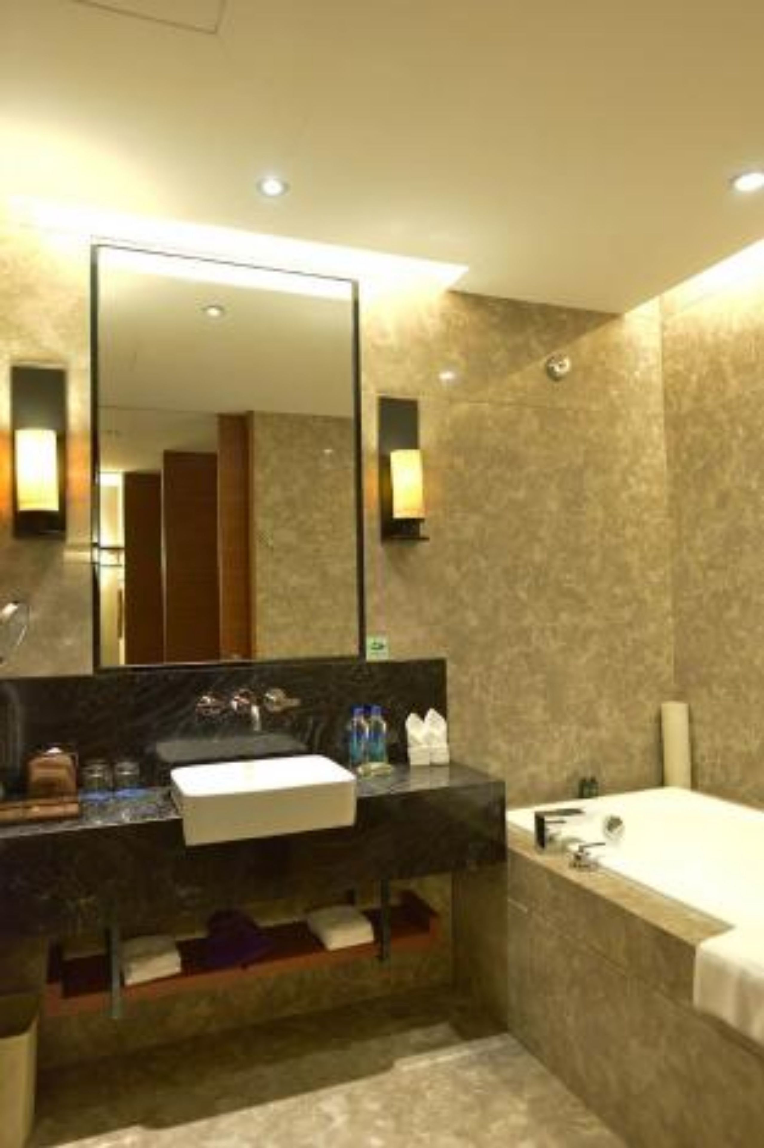 Un baño moderno con un espejo grande, un lavamanos, una bañera y un mueble de tocador con un perchero para toallas.