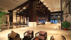 A spacious lobby with modern furniture, a reception desk, and a large plant. - Heyuan Mels Welton Evergreen Lake Hotel (Heyuan)