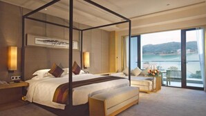 A four-poster bed with a view of the sea, a sofa, and a balcony with a railing. - Heyuan Mels Welton Evergreen Lake Hotel (Heyuan)
