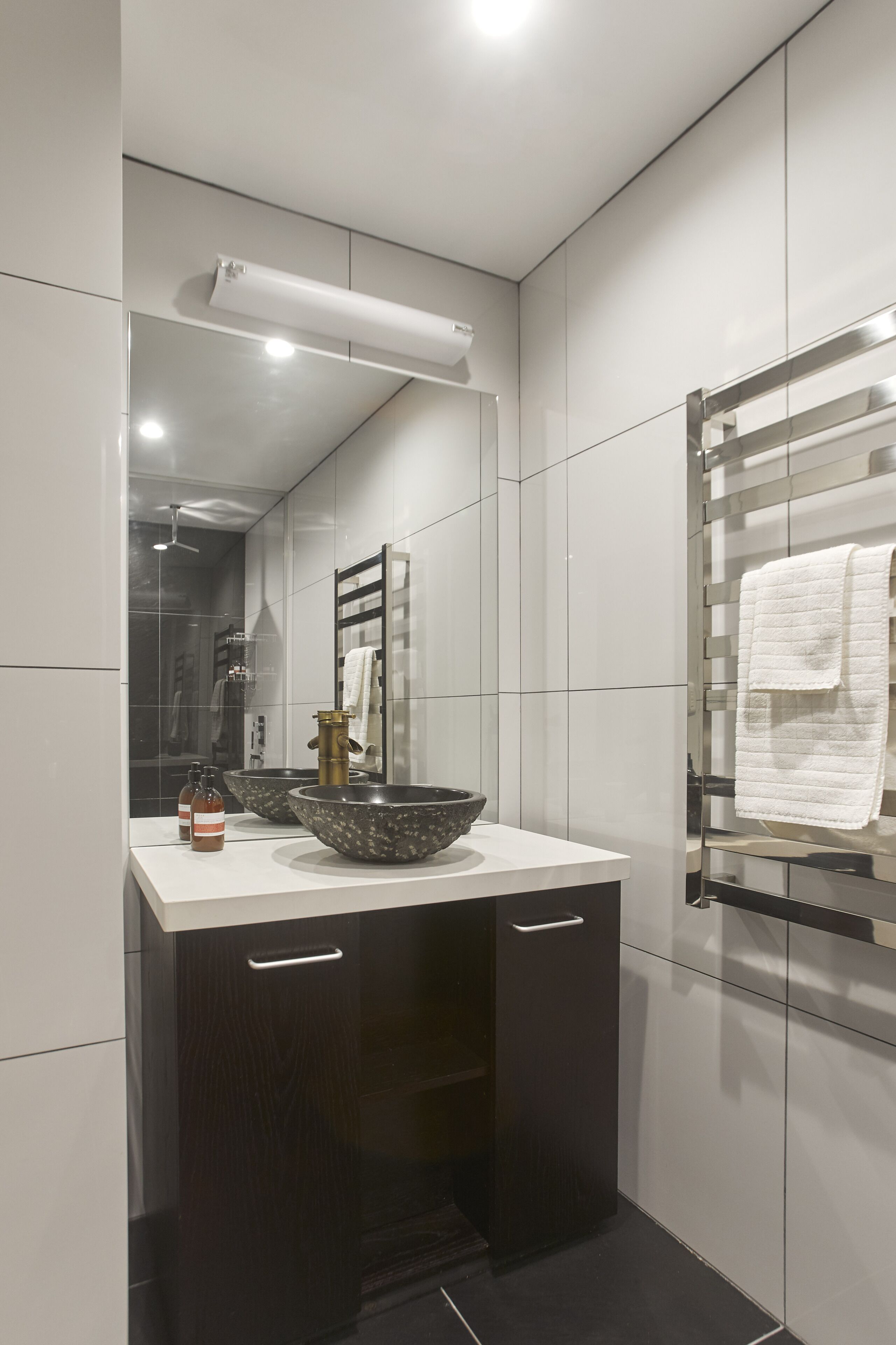 Un bagno moderno con uno specchio grande, un lavabo a incasso e un portasciugamani.