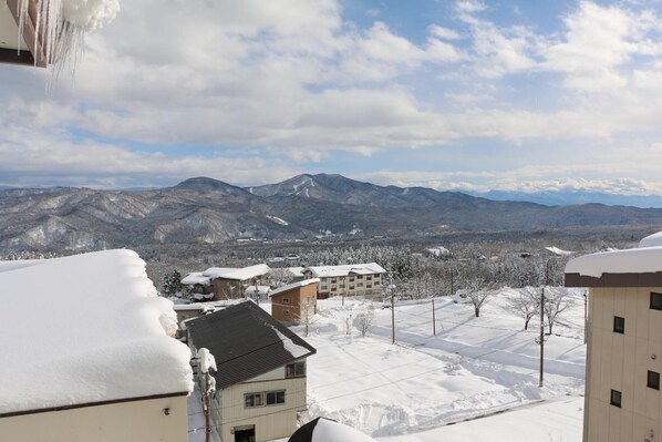 A snow-covered residential area with buildings and mountains in the background. - The Address Akakura (Myoko)
