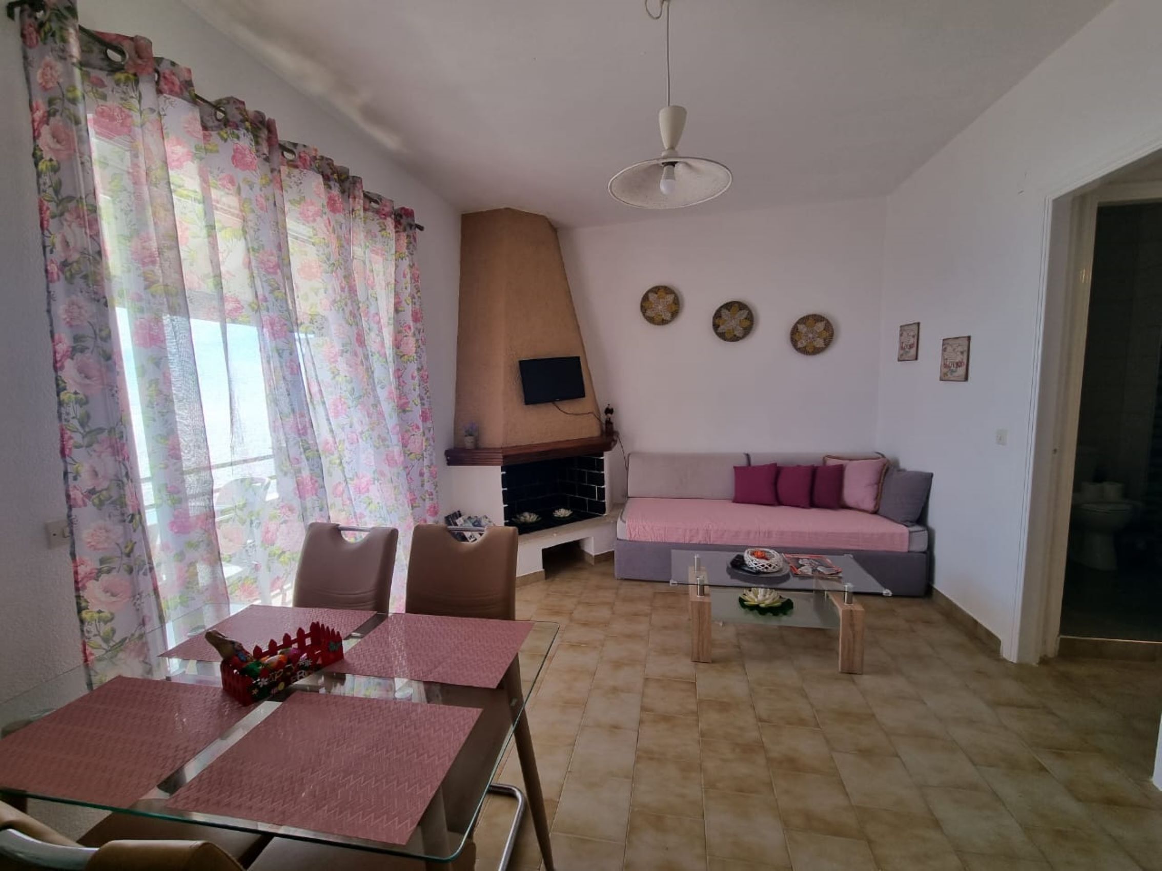 Uma sala de estar com sofá, mesa de centro e televisão fixada na parede.