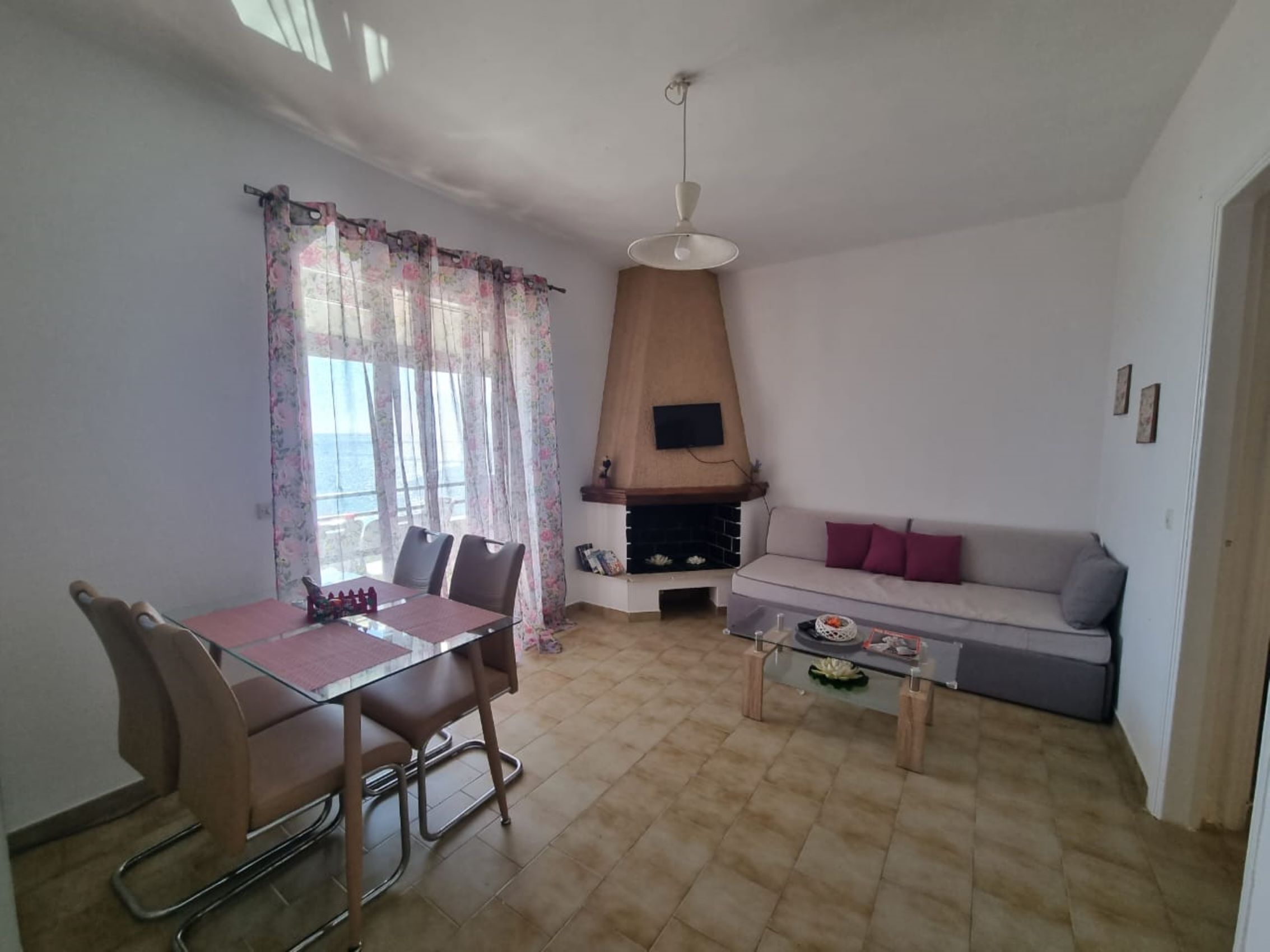 Ein Wohnzimmer mit Essbereich, einer Couch, einem Kamin und einem an der Wand montierten Fernseher.
