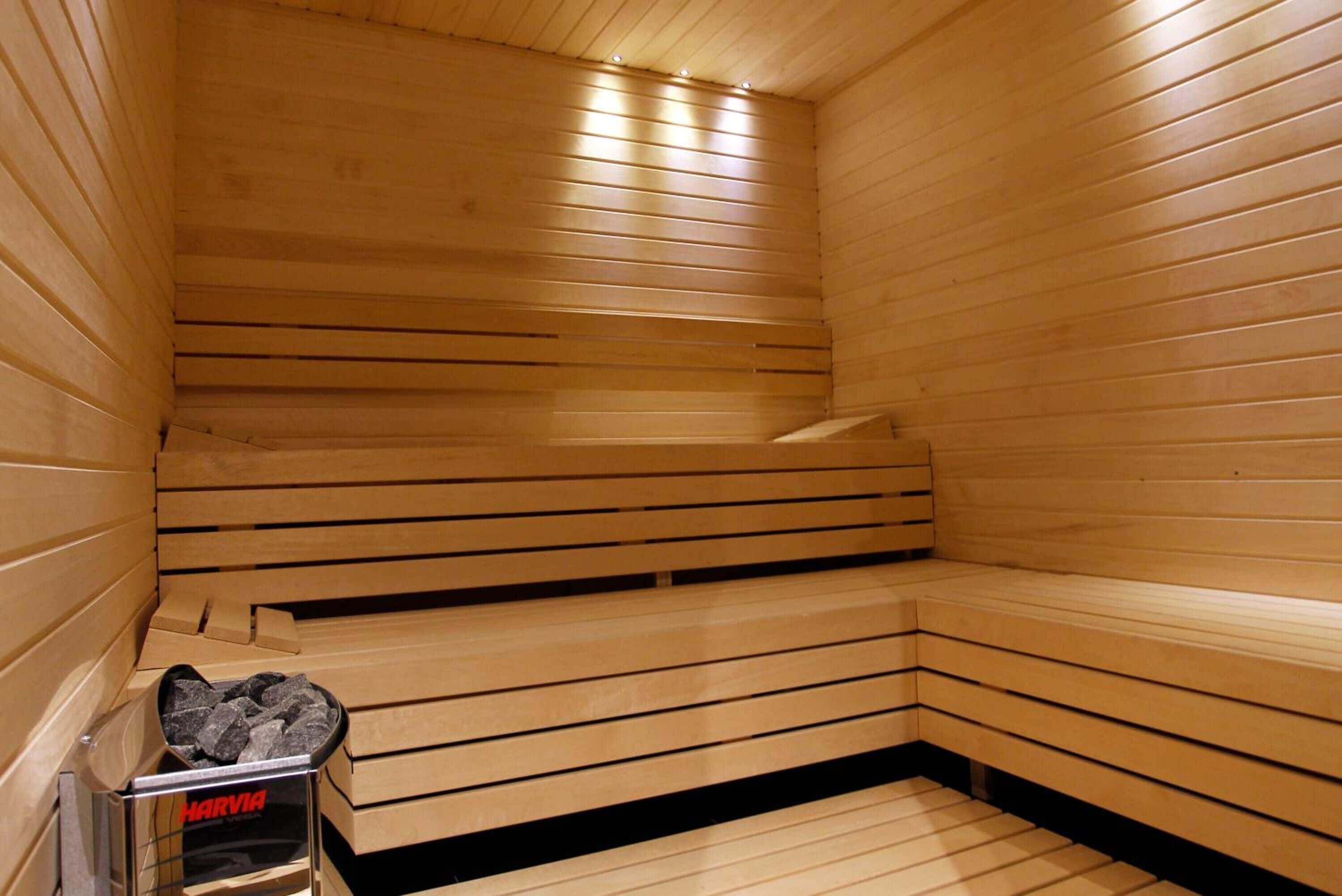 Uma sauna com bancos de madeira e aquecedor aparente.