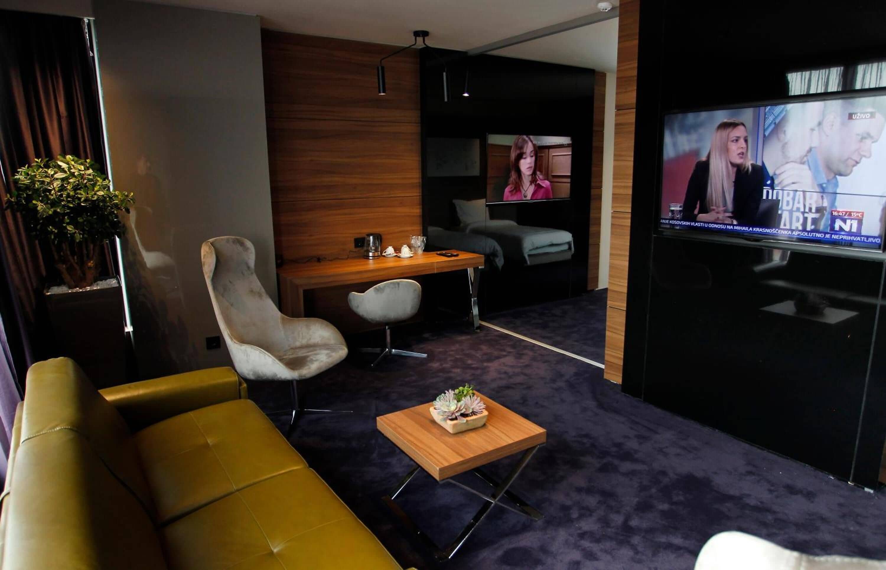 Ein modernes Wohnzimmer mit einer Couch, einem Holztisch, einem Fernseher und einem kleinen Tisch mit einer Pflanze.