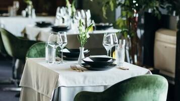 A dining table set with plates, glasses, and a vase with flowers.