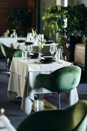 A dining table set with plates, glasses, and a vase with flowers.