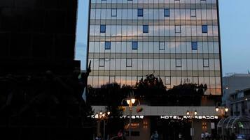 A modern hotel with a glass facade, a statue of a figure on horseback, and a sign reading "HOTEL".