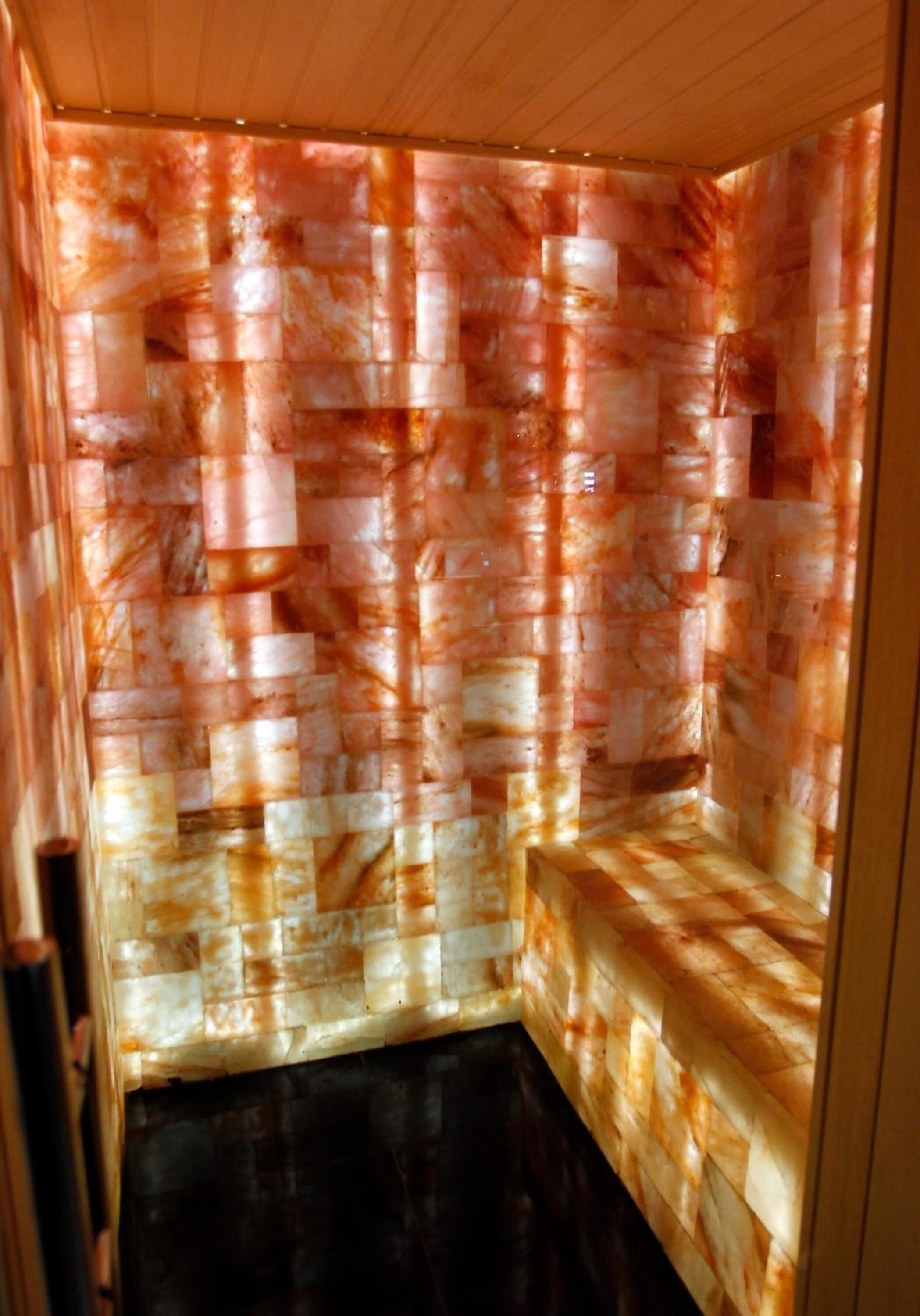 Une pièce dotée d’un mur décoré d’une mosaïque originale, d’un banc et d’un plancher foncé.