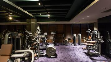 Une salle de sport équipée de divers appareils d’exercice, dotée d’un tapis violet et de murs recouverts de panneaux en bois.