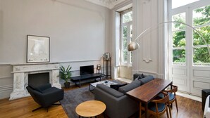 Un salon spacieux doté d’une cheminée, d’une grande fenêtre et d’un lustre moderne.