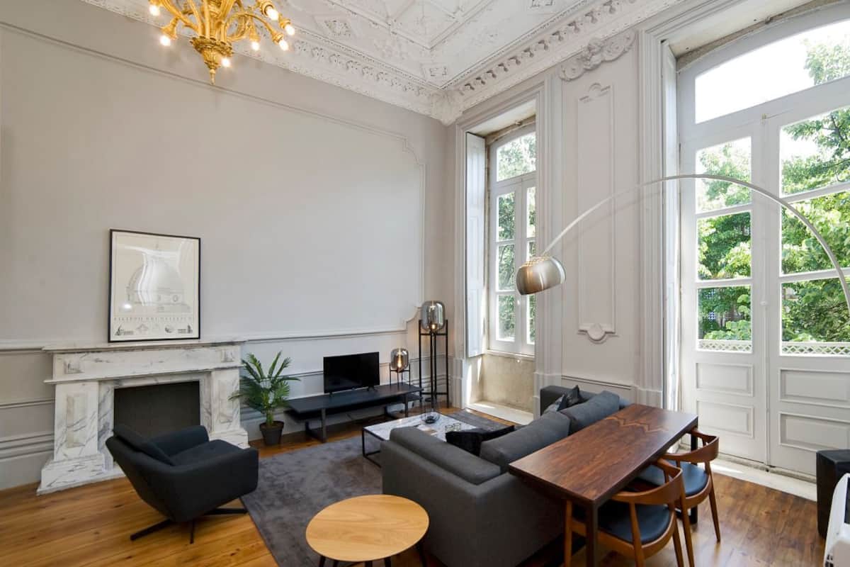 A spacious living room with a fireplace, a large window, and a modern chandelier.