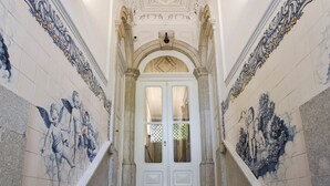 Un magnifique escalier orné de carreaux bleus et blancs, menant à une porte blanche dotée de panneaux de verre.