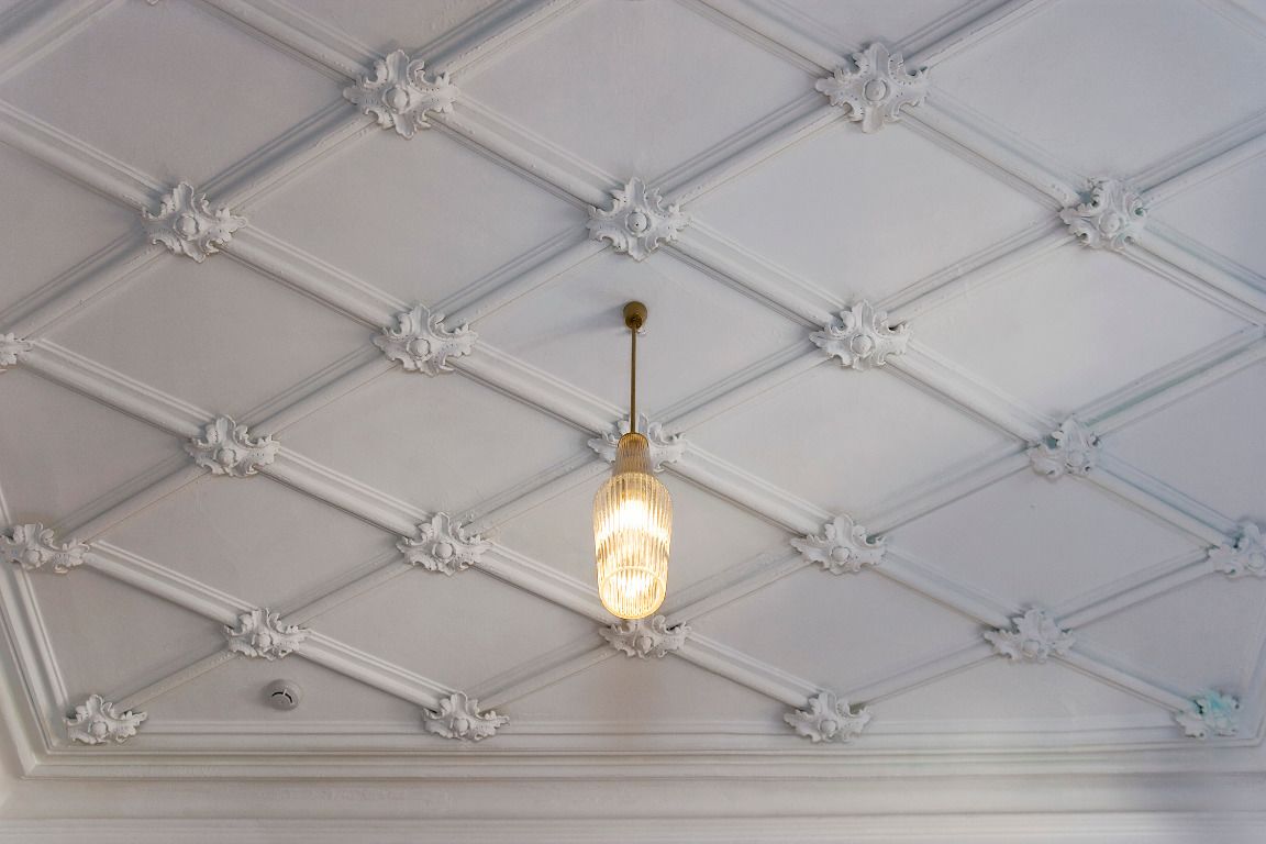 A ceiling with a geometric pattern and a hanging light fixture.