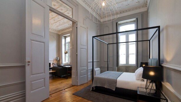 Une chambre à coucher avec un lit à baldaquin, un bureau et une chaise au fond de la pièce.