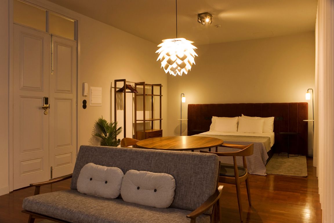 Une chambre d’hôtel comprenant un lit, un canapé, une table à manger et un luminaire suspendu.