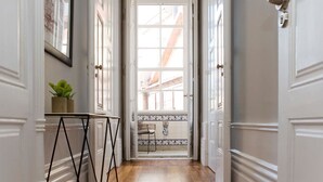 Un couloir doté d’un plancher en bois, de portes blanches et d’un hall d’entrée carrelé.