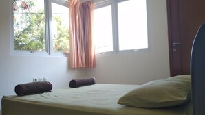 A bedroom with a bed, two pillows, a window with curtains, and a door. - De Sutami Pasteur Villa by HouseinBandung (Bandung)