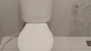 A standard white toilet with a tank and seat, positioned against a wall with a circular pattern tile design. - De Sutami Pasteur Villa by HouseinBandung (Bandung)