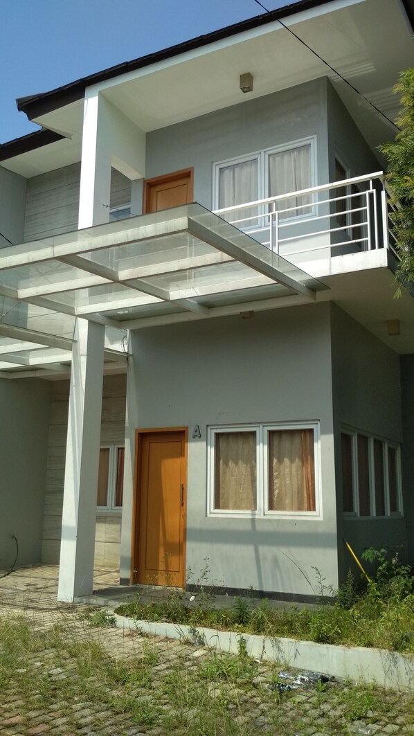 Stylish two-story residence with a large door, small window, and balcony with a railing.