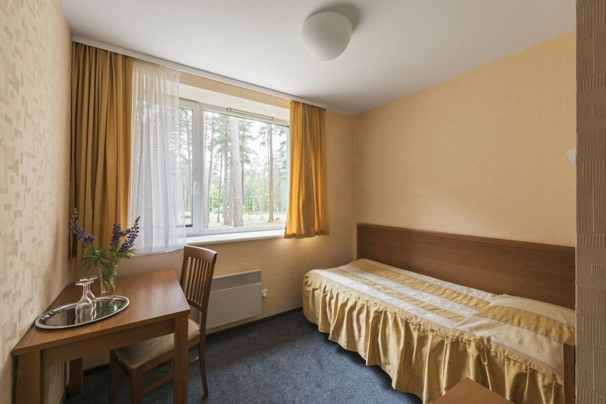 A small, tidy room with a single bed, a table with a tray, and a chair.