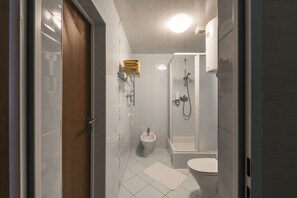 A compact bathroom with a toilet, bidet, and shower area. - ORO Dubingiai (Giraiciai)