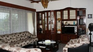 A living room with a sofa set, a coffee table, a cabinet with glass doors, and a television.