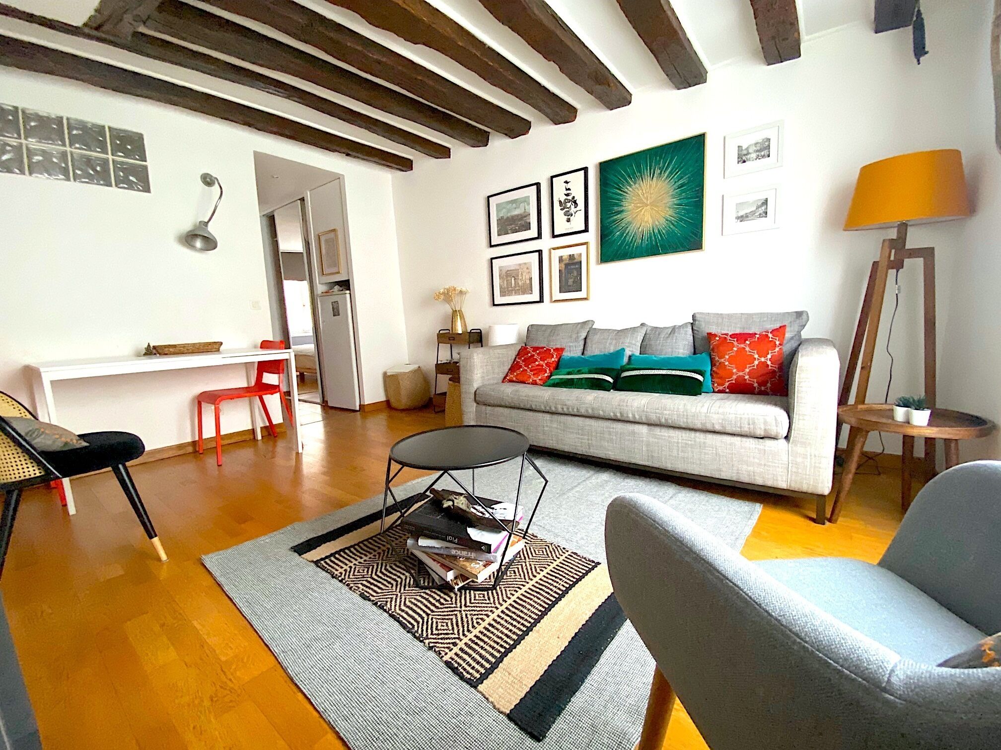 Un salon comprenant un canapé, une table basse, un coin repas avec une table et des chaises, et un tableau accroché au mur.