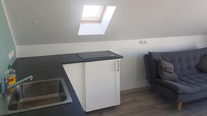 A compact kitchen with a skylight, a built-in sink, and a small white cabinet.