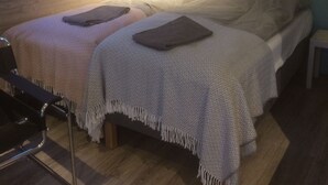 A bedroom with a skylight, two beds, a bedside table, and a chair.