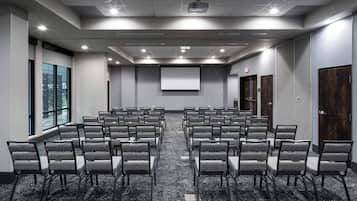 A conference room with rows of chairs, a projector screen, and a large window.