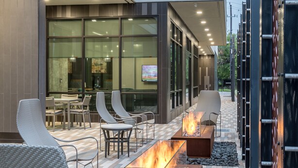 An outdoor seating area with fire pits, wicker chairs, and a checkered floor pattern. - Courtyard by Marriott Houston Heights/I-10 (Houston)