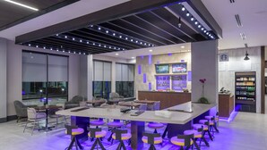 A modern bar area with a central island, bar stools, and a seating area with chairs and tables. - Courtyard by Marriott Houston Heights/I-10 (Houston)