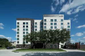 A Courtyard hotel with a modern design, featuring multiple floors and a prominent entrance. - Courtyard by Marriott Houston Heights/I-10 (Houston)