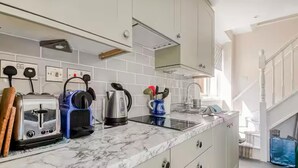Una cocina con encimera de mármol, hervidor, tostadora y cafetera.