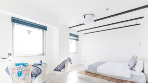 Une chambre à coucher moderne, avec un lit, un bureau et deux chaises.