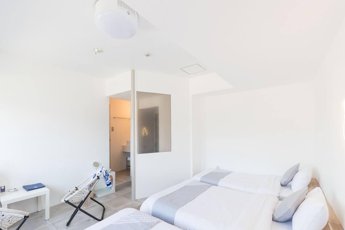 Une chambre d’hôtel moderne avec deux lits, un petit bureau et une chaise.