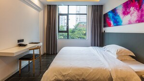 Une chambre d’hôtel avec un lit, un bureau et une fenêtre avec des rideaux.