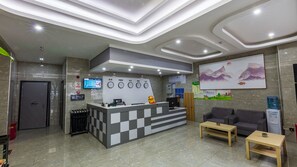 A reception area with a check-in counter, a digital display, a clock, a water dispenser, and a sofa. - Sucha Hotel Chengdu Hongpailou Station (Chengdu)