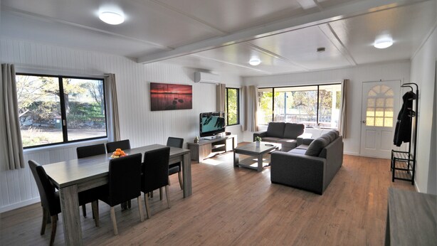 A modern living room with a dining area, a sofa, a TV, and a coat rack.