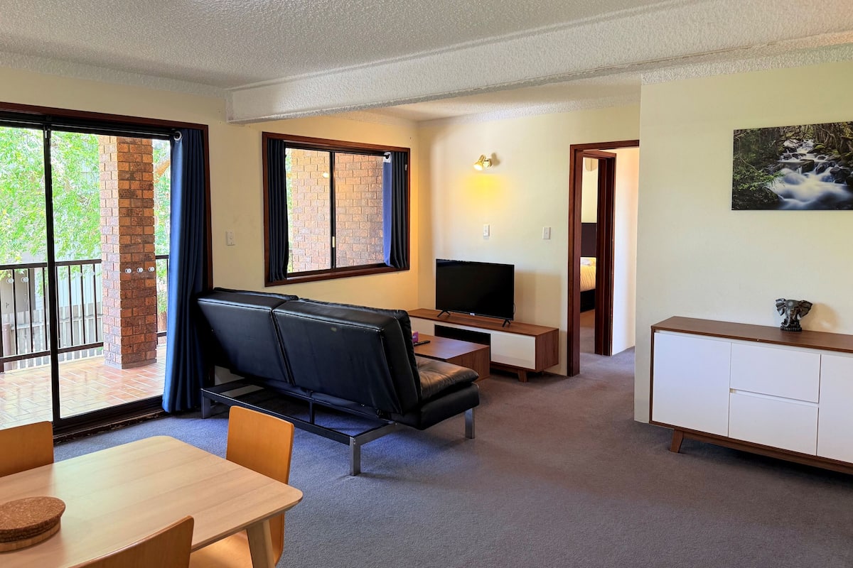 Una sala de estar moderna con sofá, televisor y zona de comedor.