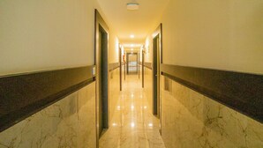 A corridor with marble flooring and dark trim, leading to a door at the end. - Capital O 36457 Boulevard Madiwala (Bengaluru)