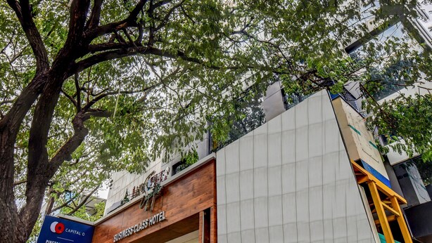 A business class hotel with a prominent sign, large windows, and a view of the surrounding area. - Capital O 42226 Pine Tree Signature (Chennai)