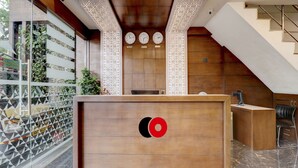 A reception desk with a logo, a staircase, and a wall clock. - Capital O 42226 Pine Tree Signature (Chennai)