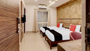 A hotel room with two beds, a ceiling fan, an air conditioning unit, a TV, and a wooden panel wall. - Capital O 42226 Pine Tree Signature (Chennai)